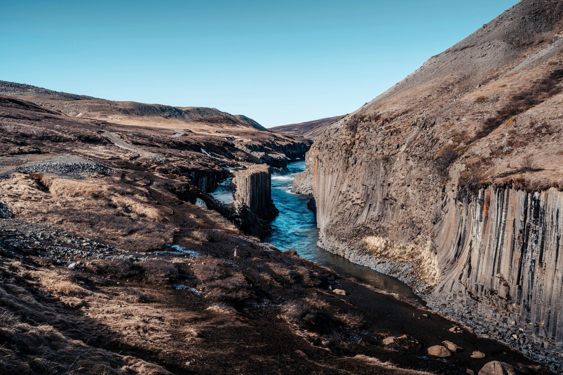The blue river running through Stuðlagil canyon between basalt columns