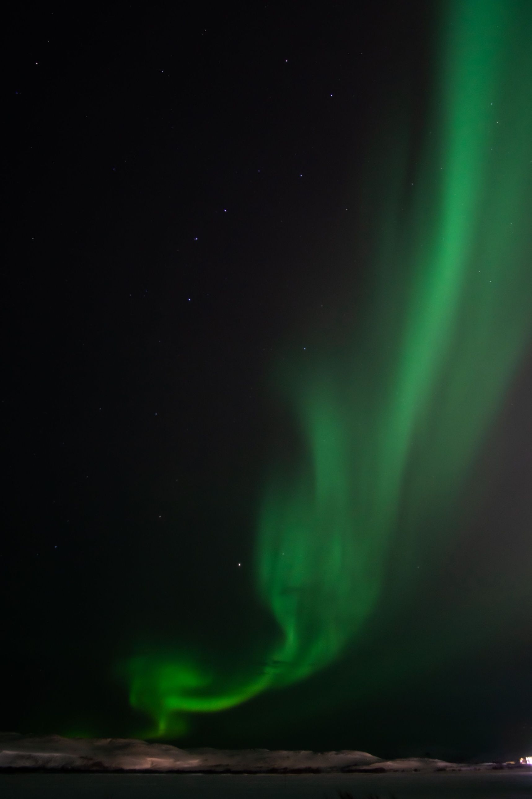 A green aurora curving down to a snowy horizon